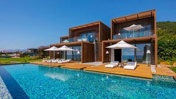 Un resort moderno con piscina, terraza de madera y sillones de descanso.