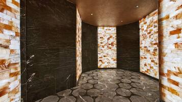 A room with hexagonal stone flooring, dark marble walls, and a textured wall panel.