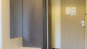 Un pasillo con un banco, una puerta con un cartel y un piso de baldosas.