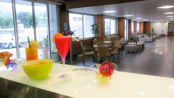 A hotel lobby with a reception desk, seating area, and large windows offering a view of the street.