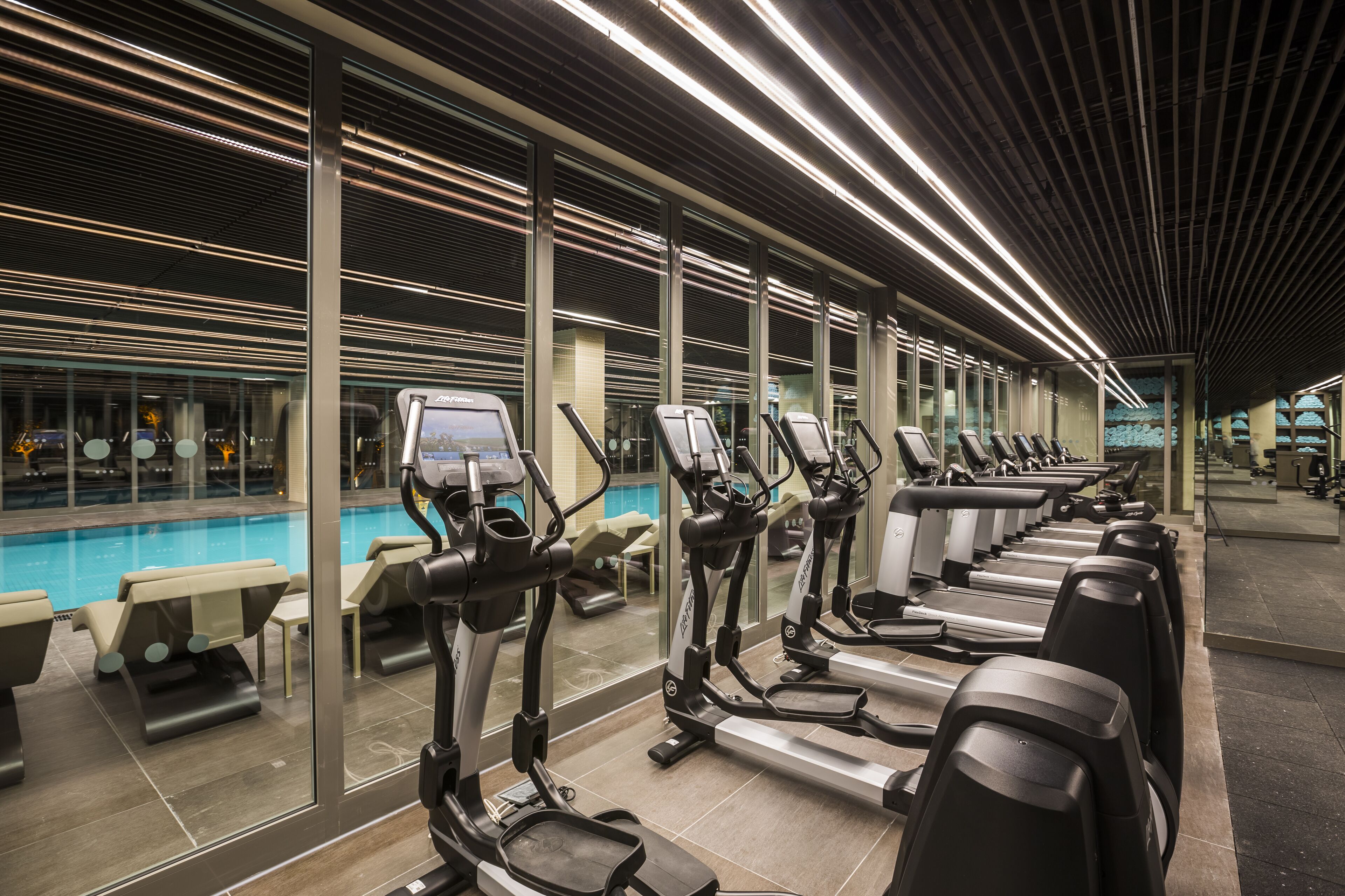 Un gimnasio con equipo de ejercicio, piscina y zonas de estar.