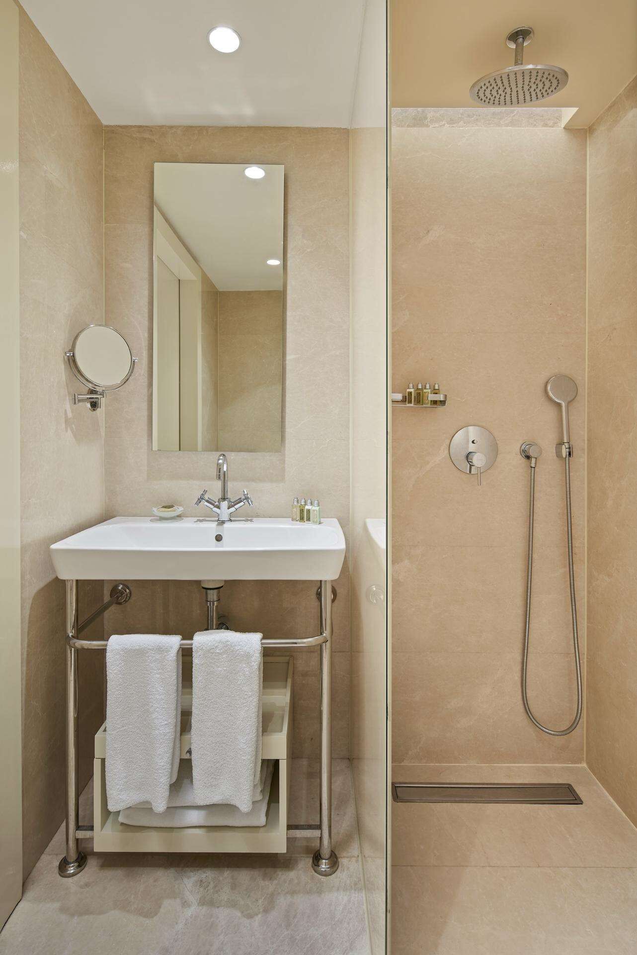 Een moderne badkamer met een wastafel, spiegel en douche.