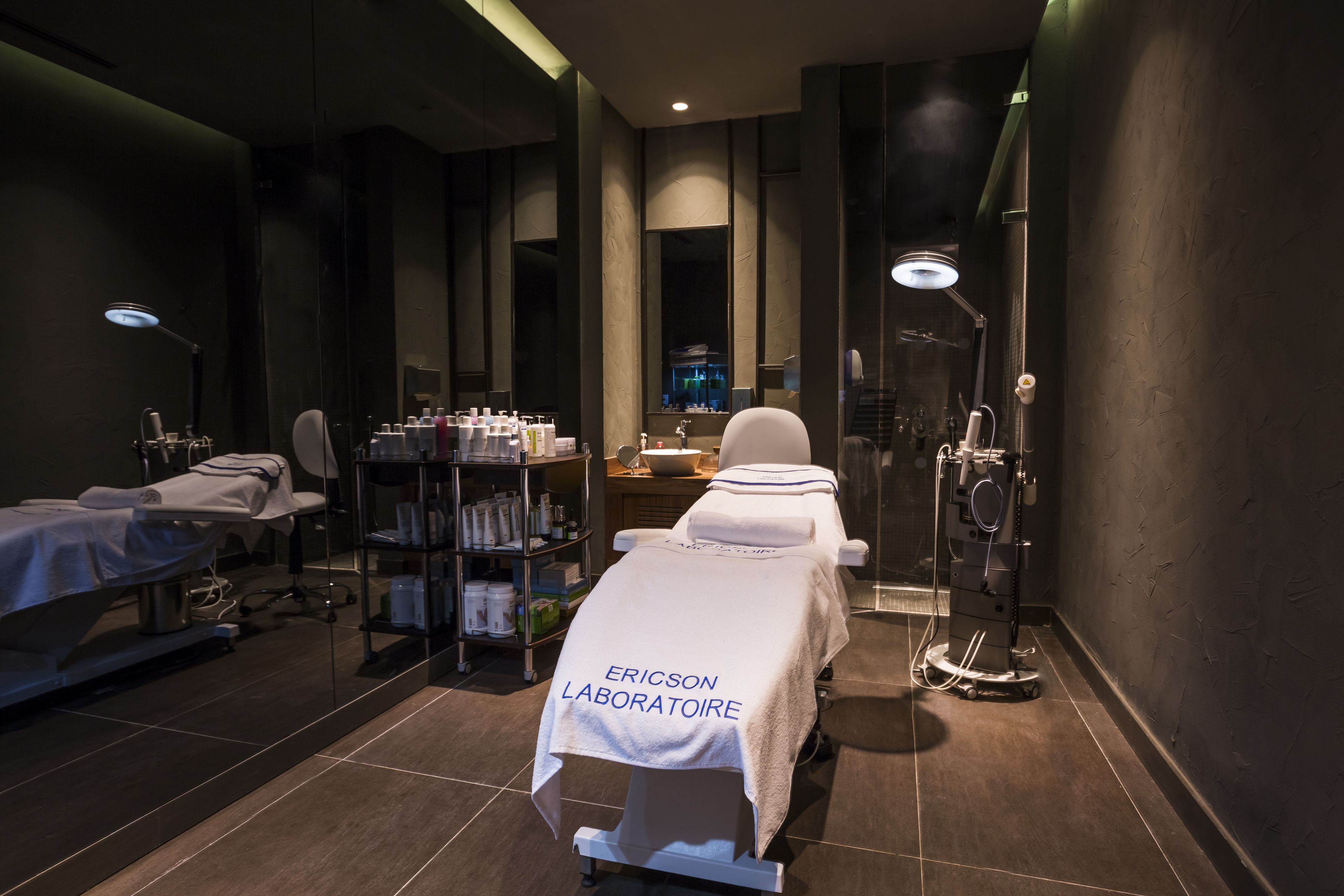 Un spa moderno con una camilla de masaje, un estante de artículos de aseo y un box de ducha de vidrio.