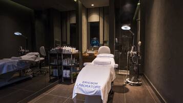 Un spa moderno con una camilla de masaje, un estante de artículos de aseo y un box de ducha de vidrio.