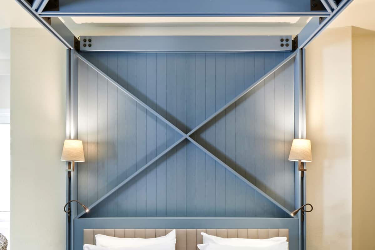 A bed with a geometric headboard, two bedside lamps, and a patterned bedspread.