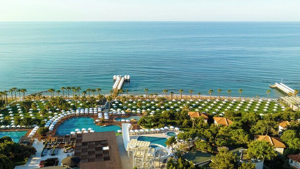A resort with multiple swimming pools, a pier, and beach umbrellas. - Voyage Sorgun (Manavgat)