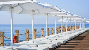 A row of white sun loungers with umbrellas on a wooden deck by the sea. - Voyage Sorgun (Manavgat)