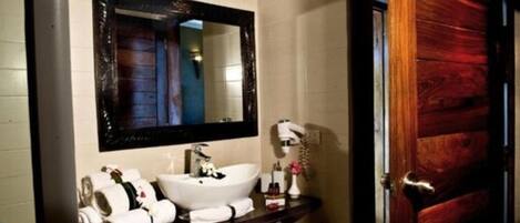 A bathroom with a white sink, a large mirror, and a wooden door.
