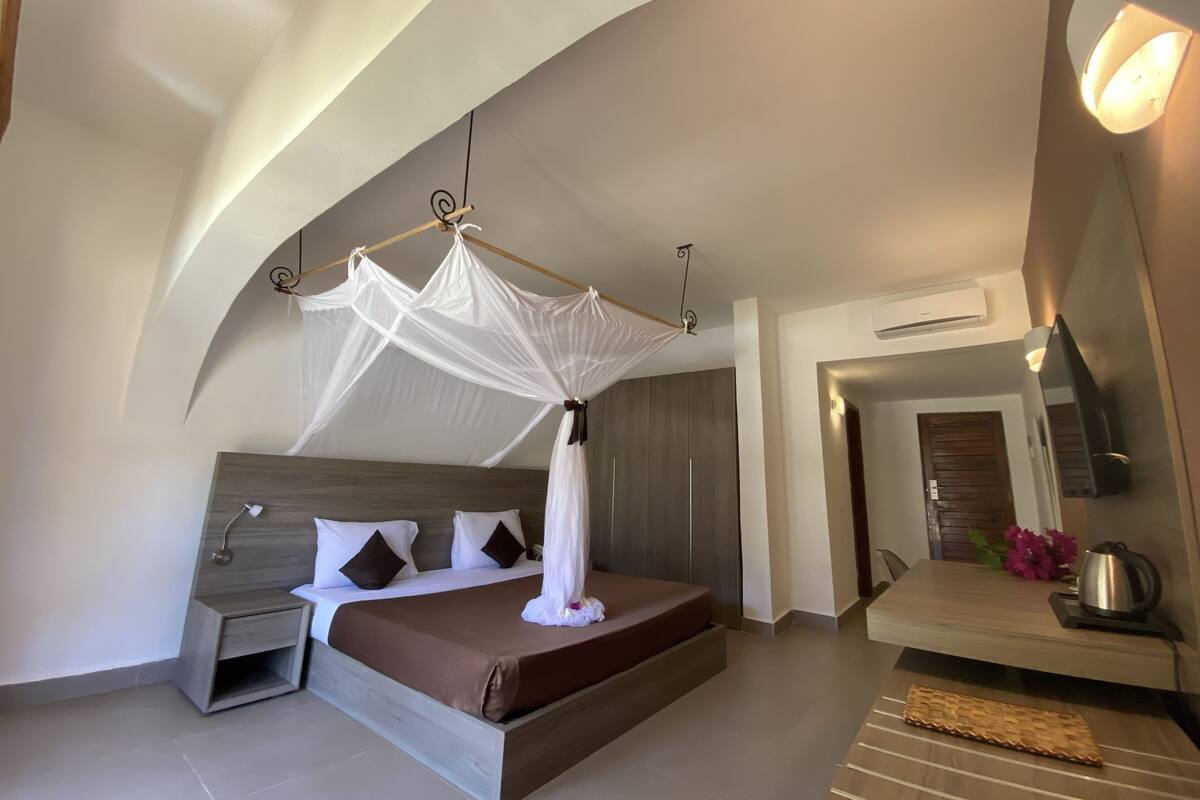 A modern bedroom with a canopy bed, a bedside table, a nightstand, and a built-in bench with a kettle.