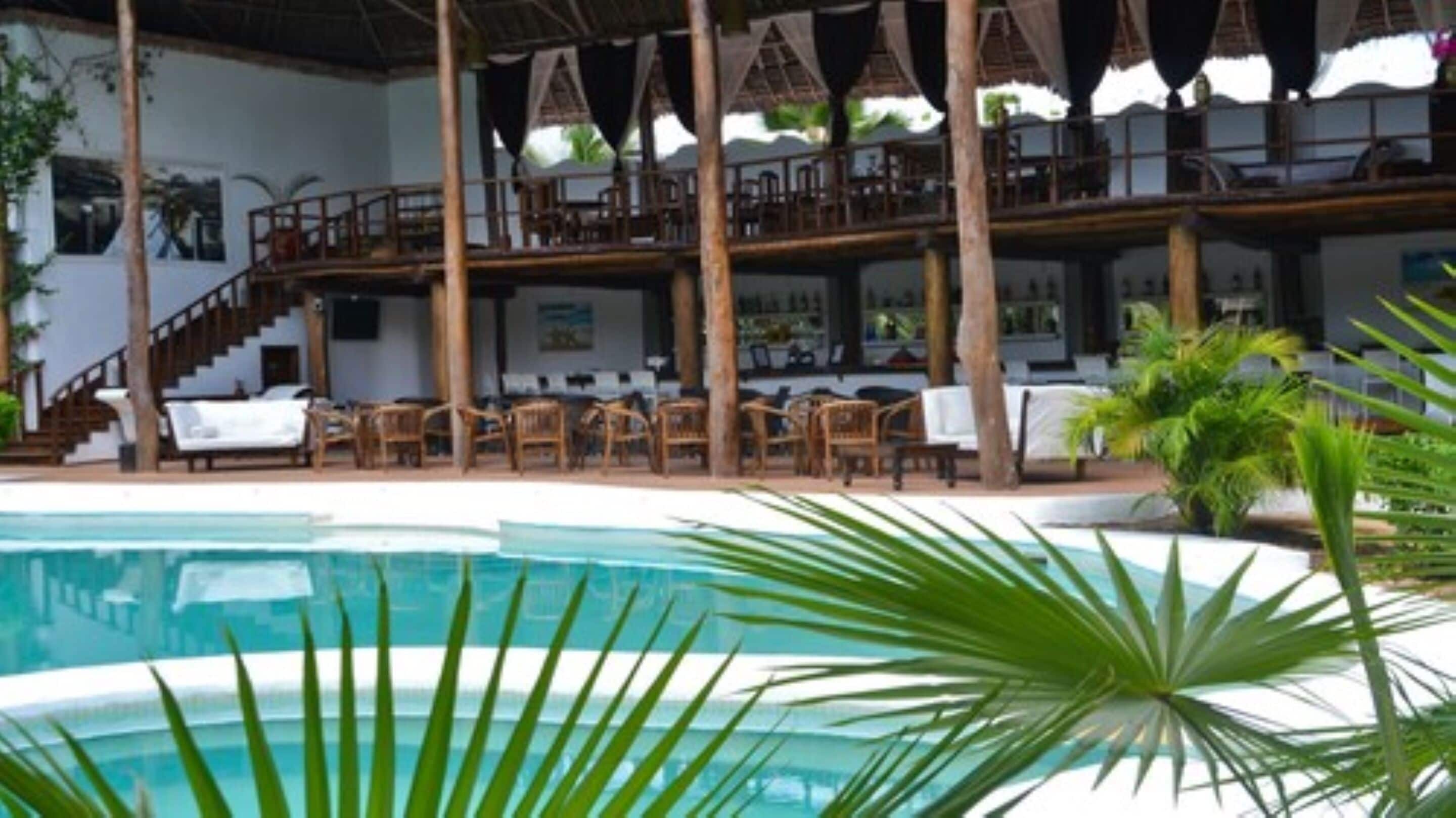 A pool area with lounge chairs and umbrellas, a staircase, and a bar area with seating.