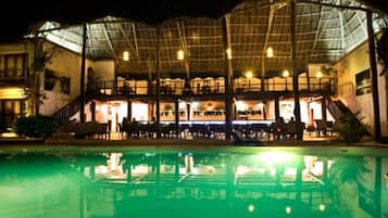 A hotel with a pool, outdoor seating, and a covered patio area.
