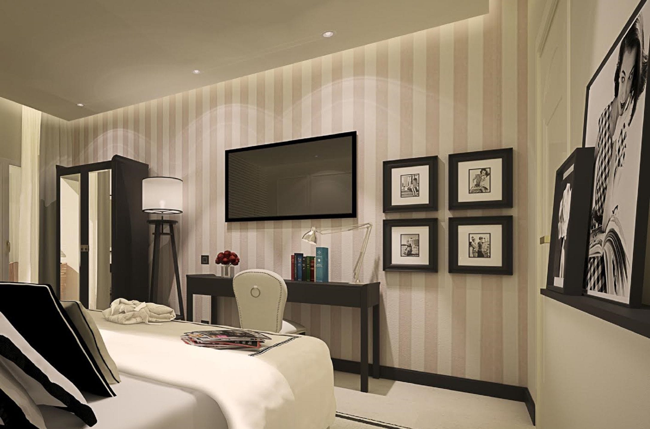 Habitación de hotel con cama, escritorio, silla, lámpara y televisor de pantalla plana montado en la pared.