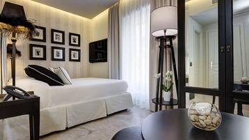 Habitación de hotel con cama, mesita de noche, lámpara y una pared decorada con cuadros.