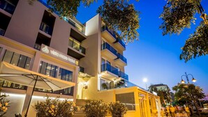 Un hotel moderno con suelo exterior a cuadros, asientos exteriores y una entrada visible.