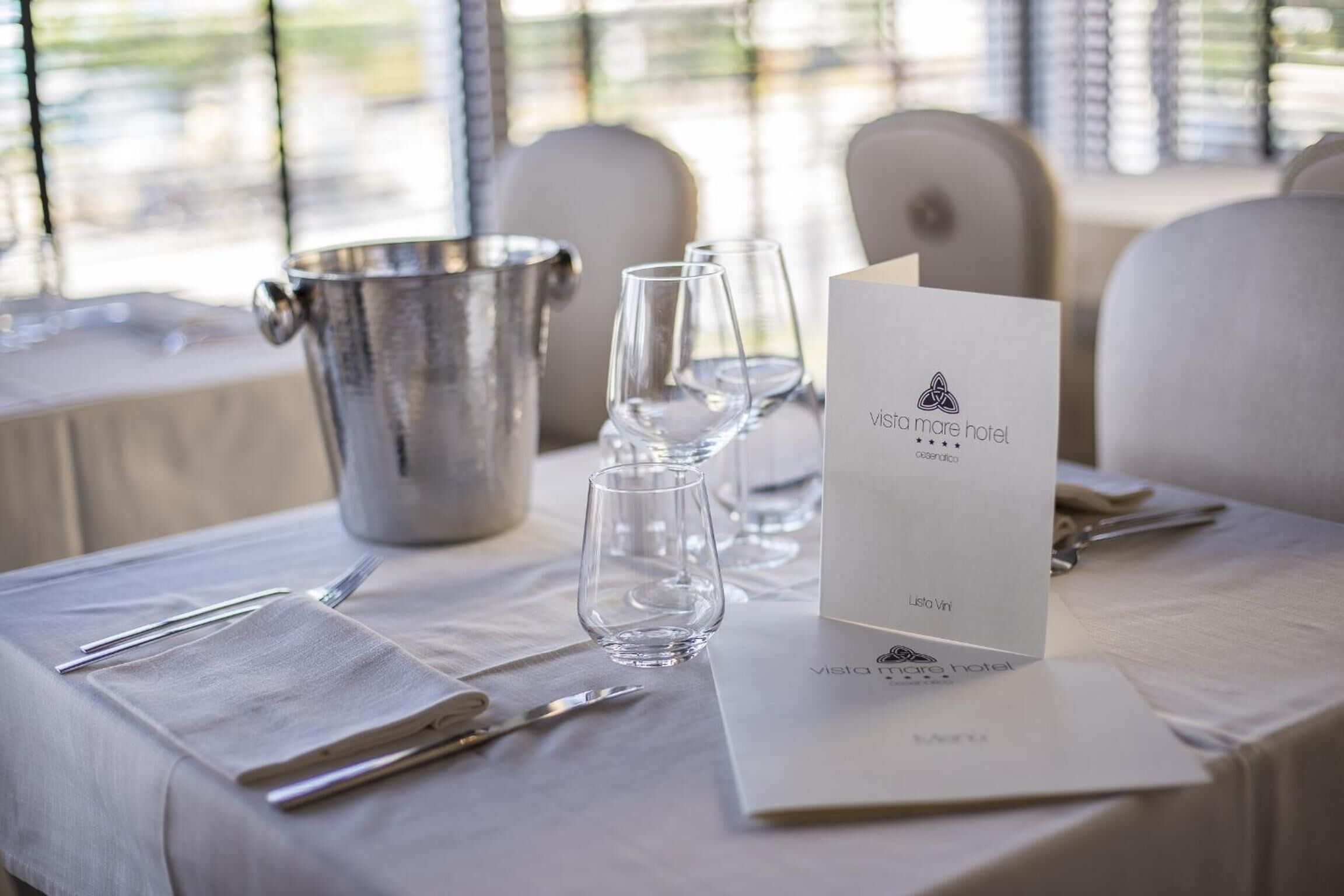A neatly set dining table with a menu, wine glasses, and cutlery, indicating a formal dining experience.