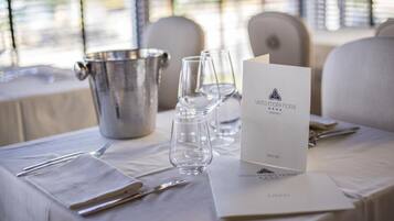 A neatly set dining table with a menu, wine glasses, and cutlery, indicating a formal dining experience.