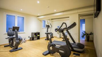 Une salle de sport à domicile équipée d’appareils de cardio, d’un tapis de course et d’un vélo d’appartement.