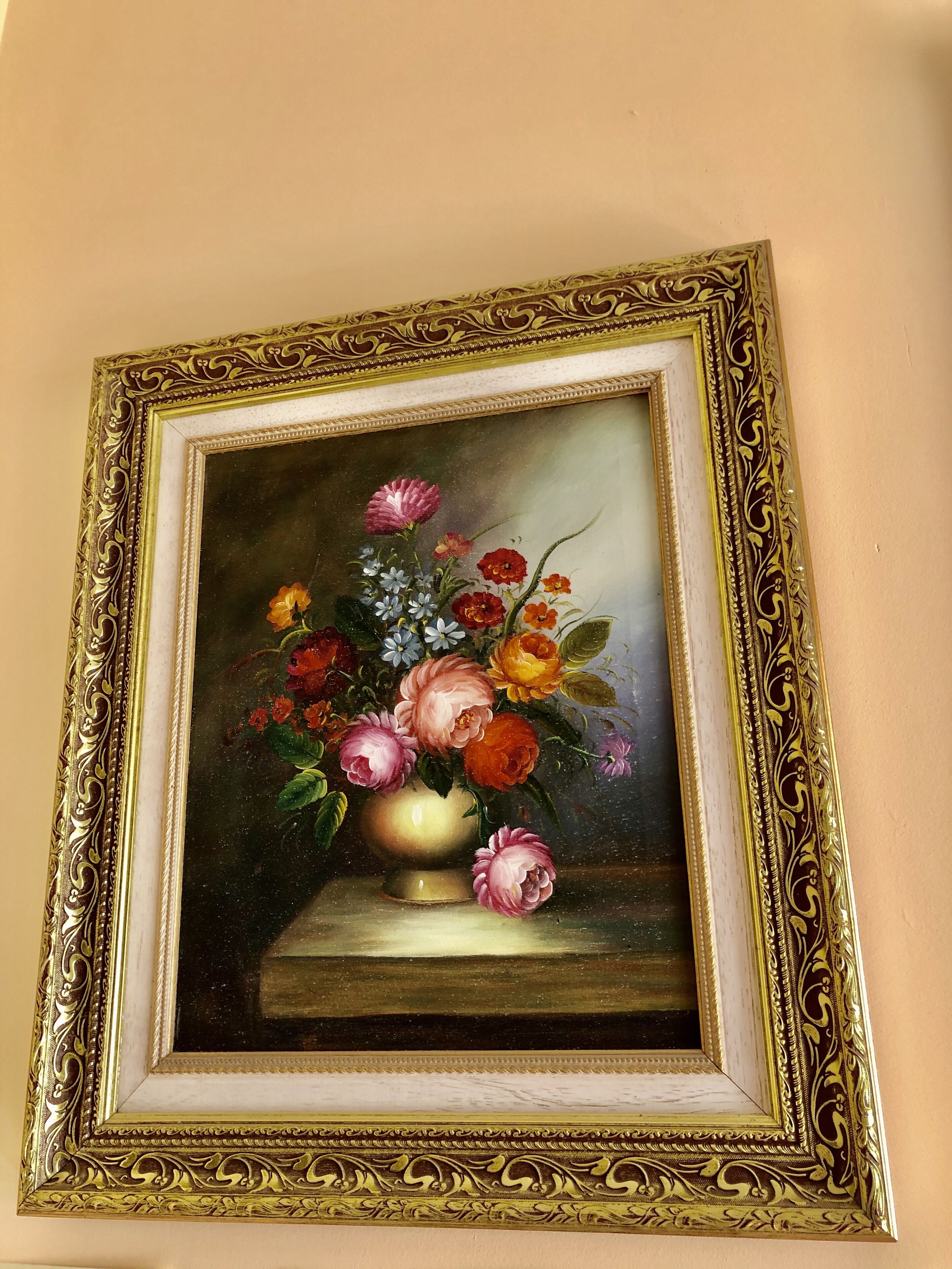 A framed painting of a still life with flowers and a vase.