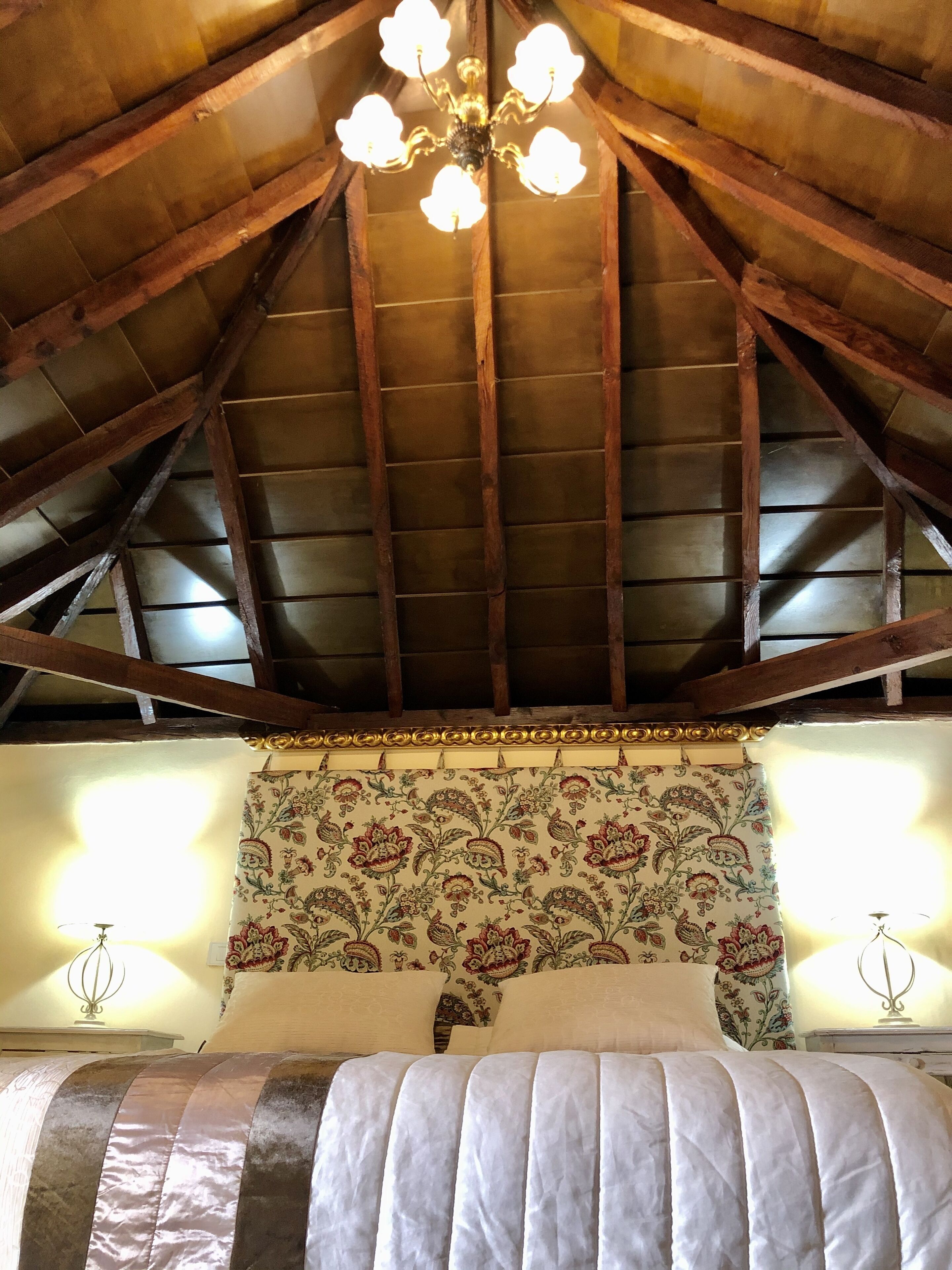 Une chambre à coucher avec un plafond en voûte, un lit doté d’une tête de lit à motifs et deux lampes de chevet.