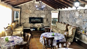 A rustic dining area with stone walls, wooden beams, and a television mounted on the wall. - Hotel Rural Vilaflor (Vilaflor)