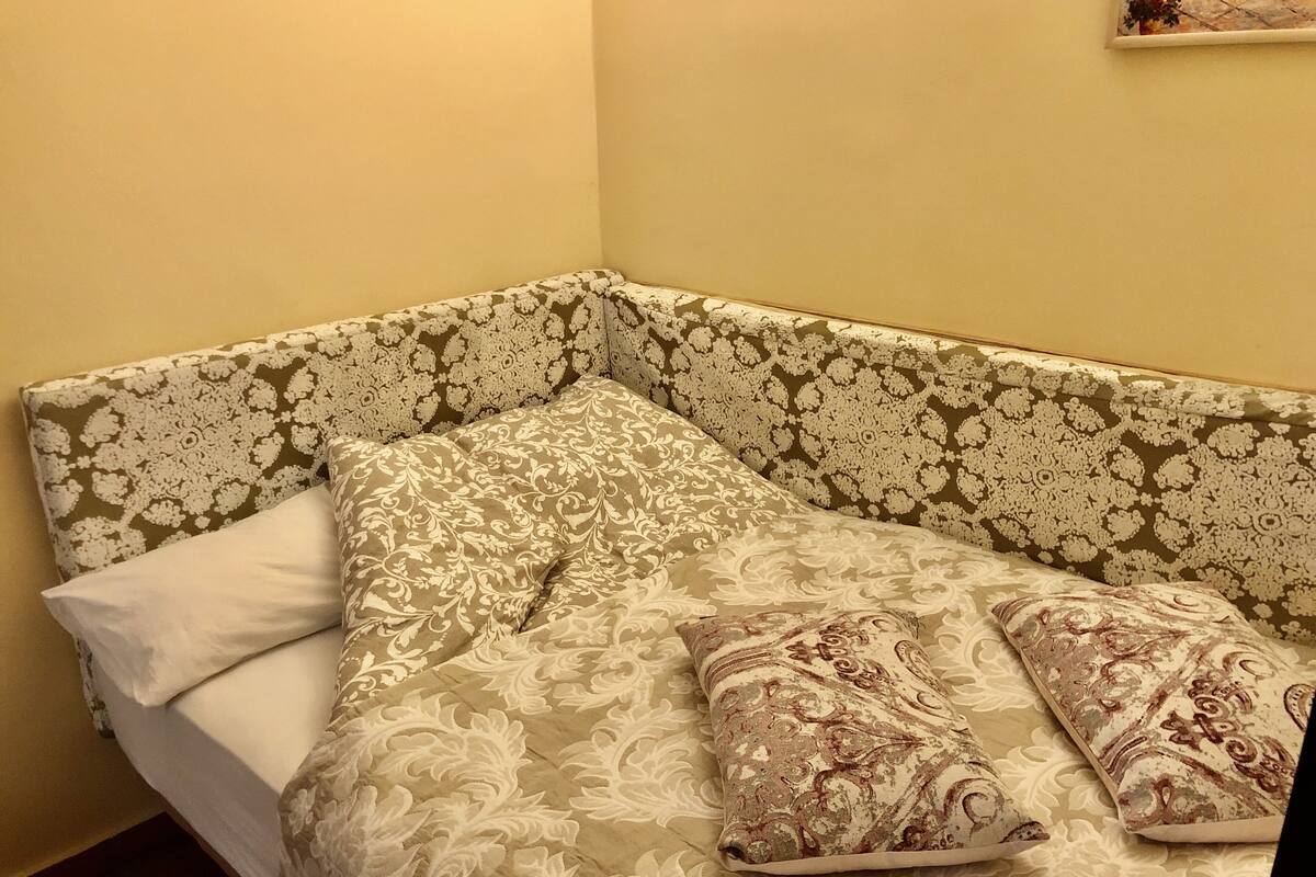 A corner sofa with patterned upholstery, a white pillow, and two decorative pillows.