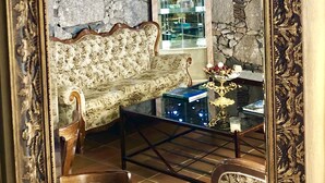 A room with a stone wall, a patterned sofa, a wooden chair, a glass coffee table, and a hanging light fixture. - Hotel Rural Vilaflor (Vilaflor)