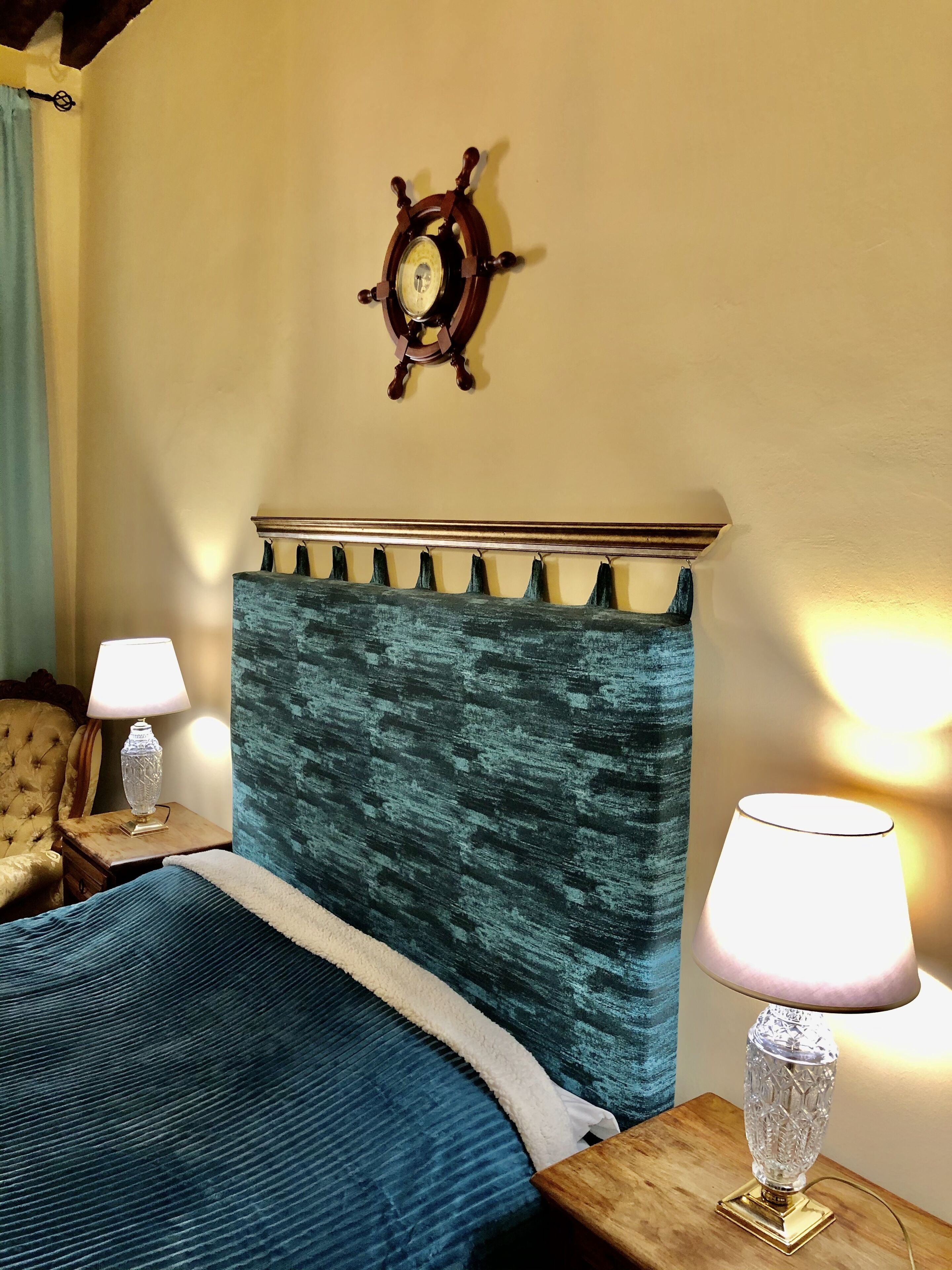 Un dormitorio con cama, dos mesitas de noche, un reloj de pared y una lámpara.