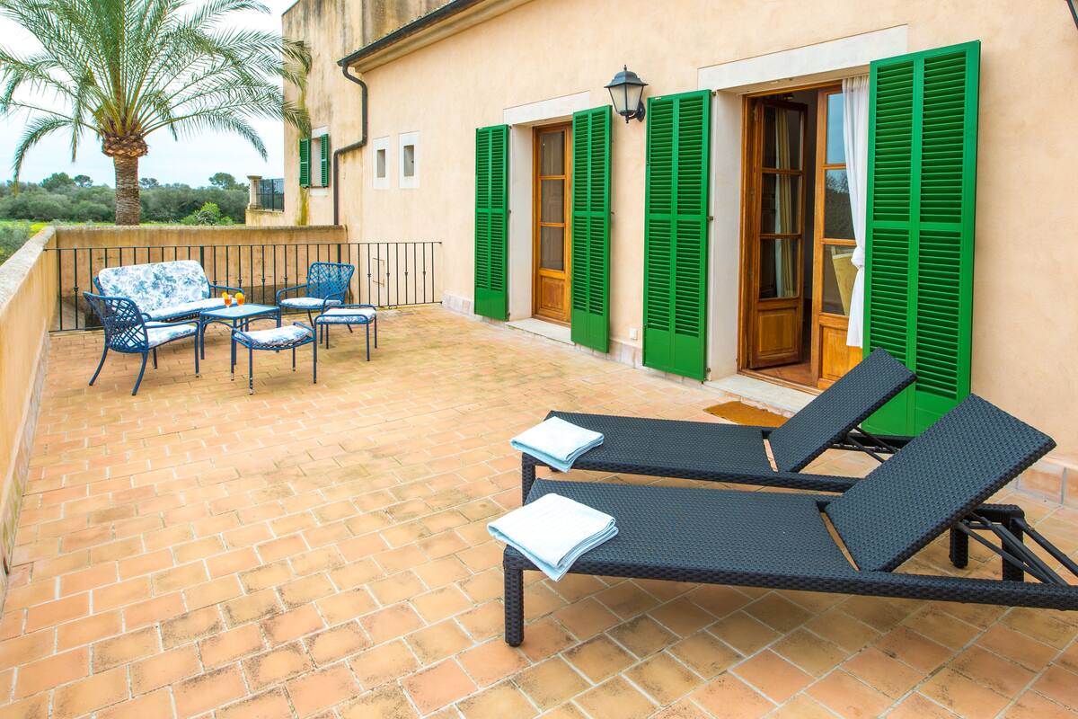 A terrace with two lounge chairs, a table, and a chair.