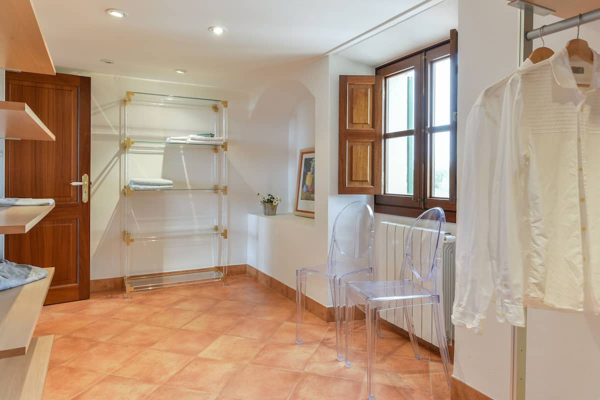 A room with a wooden door, a glass shelf, a radiator, and a window with curtains.