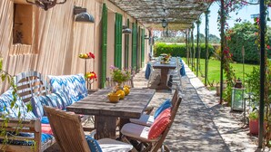 An outdoor patio with a wooden table and chairs, green shutters, and a garden view. - Agroturismo Fincahotel Es Llobets - Adults Only (Llucmajor)