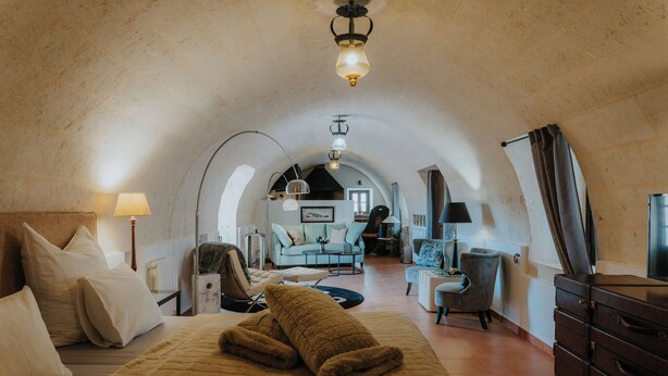 A cozy, well-lit room with a bed, a sofa, and a dresser. There is a lamp on the dresser and another on the nightstand. The room has a rustic, arched ceiling. - Agroturismo Fincahotel Es Llobets - Adults Only (Llucmajor)