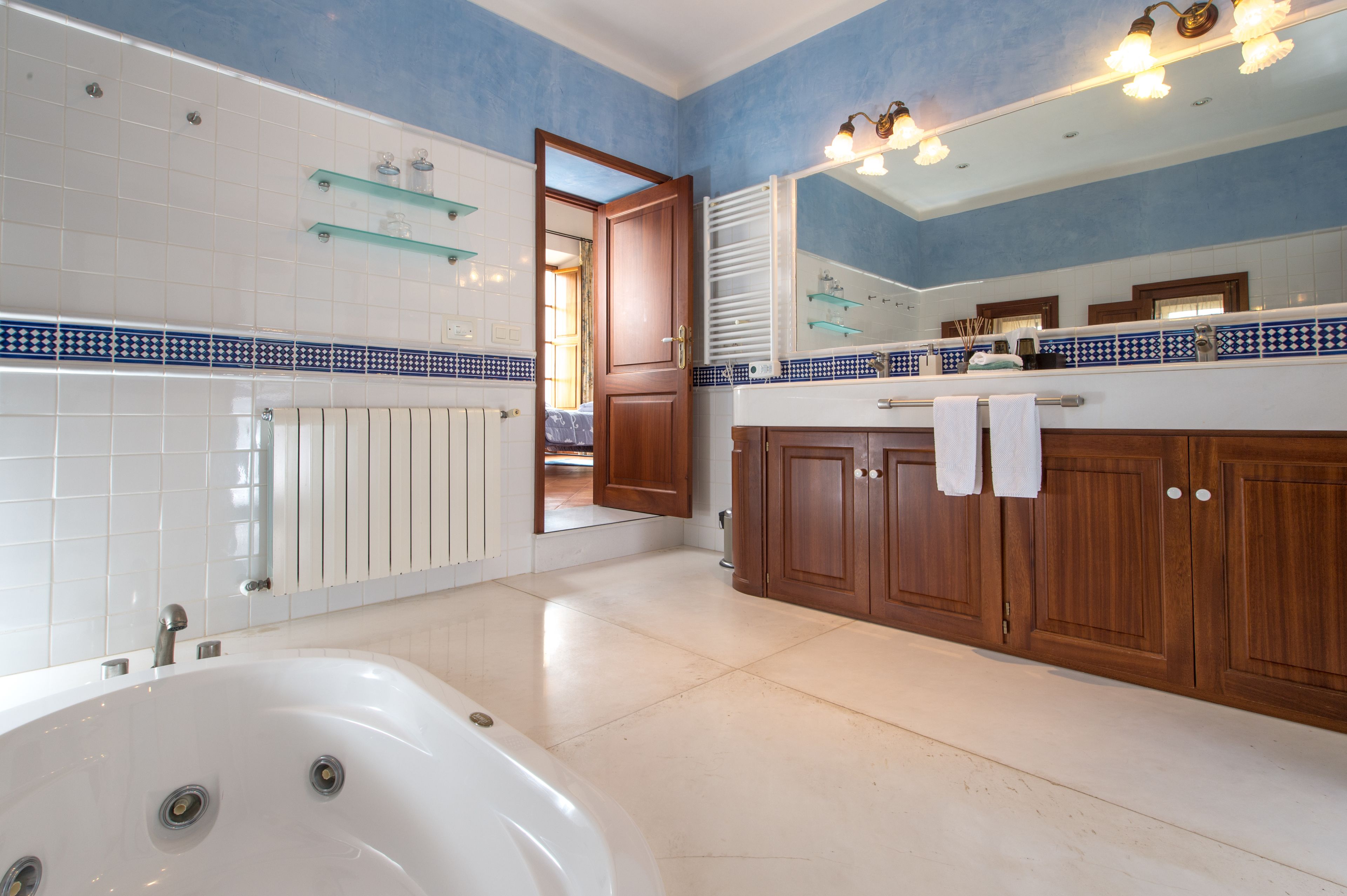 A modern bathroom with a bathtub, wooden cabinets, and a large mirror.