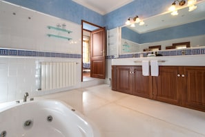 A modern bathroom with a bathtub, wooden cabinets, and a large mirror. - Agroturismo Fincahotel Es Llobets - Adults Only (Llucmajor)