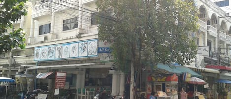 A street scene with parked scooters, a tree, and buildings with signs.
