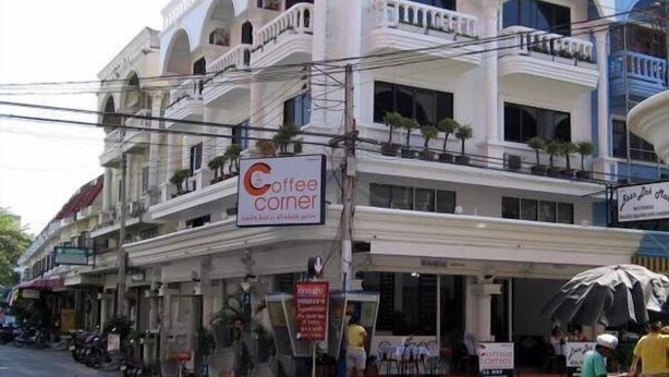 Un immeuble à plusieurs étages, avec une enseigne indiquant « Coffee Corner » au rez-de-chaussée.