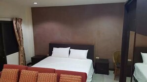 Une chambre d’hôtel avec un grand lit, un canapé rouge, une petite table et une chaise.