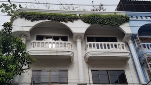 Un immeuble doté de deux balcons, chacun orné d’une balustrade et d’une fenêtre. On peut voir des lignes électriques au-dessus de l’immeuble.