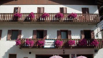 Un edificio con un letrero que indica 'Zimmer' (habitación) y balcones adornados con flores.