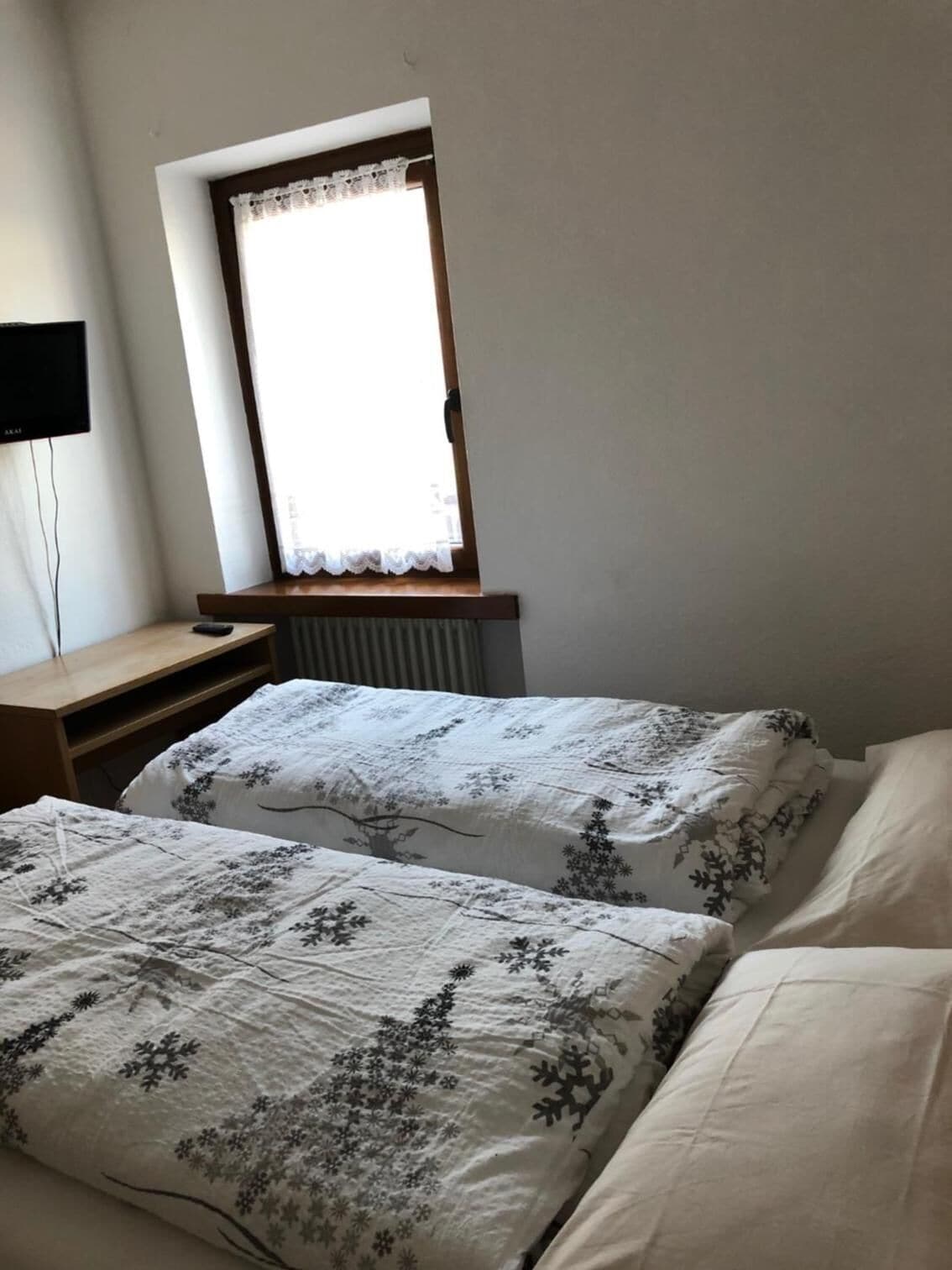 Ein Schlafzimmer mit zwei Betten, einem Schreibtisch und einem Fenster mit Vorhang.