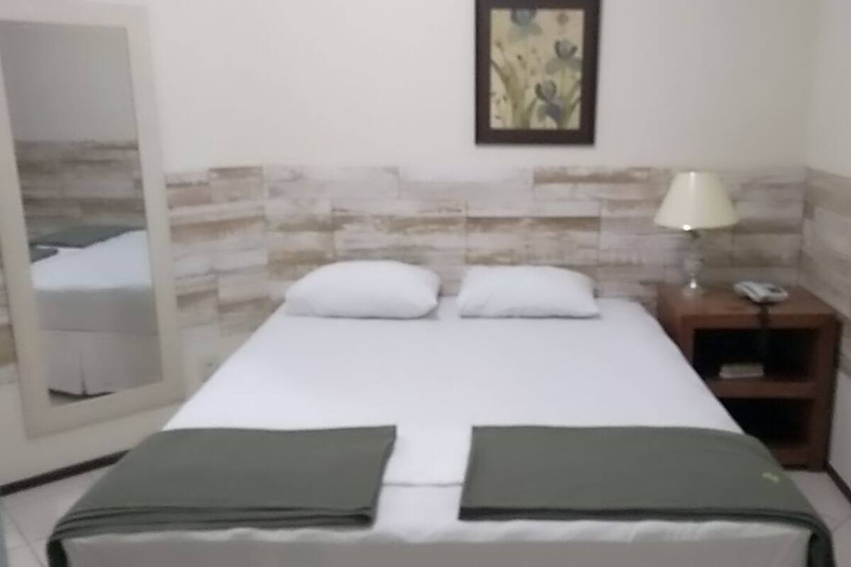 Ein Hotelzimmer mit Bett, Nachttisch, Lampe und einem Bild an der Wand.