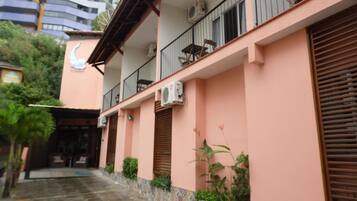 A building with a pink facade, multiple balconies, and air conditioning units.