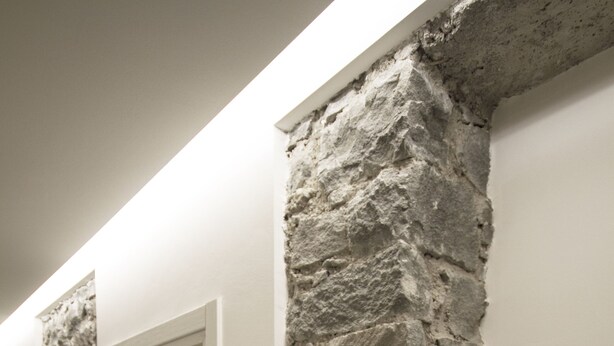 A hallway with stone walls and numbered doors, indicating a hotel or apartment complex. - Hotel Venezia (Rocca Pietore)