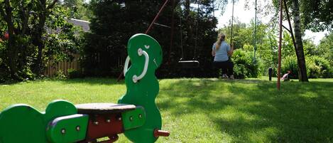A playground with a heart-shaped swing set and a swing set in a grassy area.