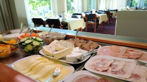 Buffet com diversos alimentos, incluindo queijos, carnes e legumes.