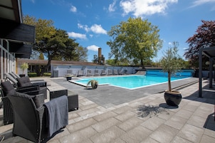 Una piscina al aire libre de temporada, sillones reclinables de piscina