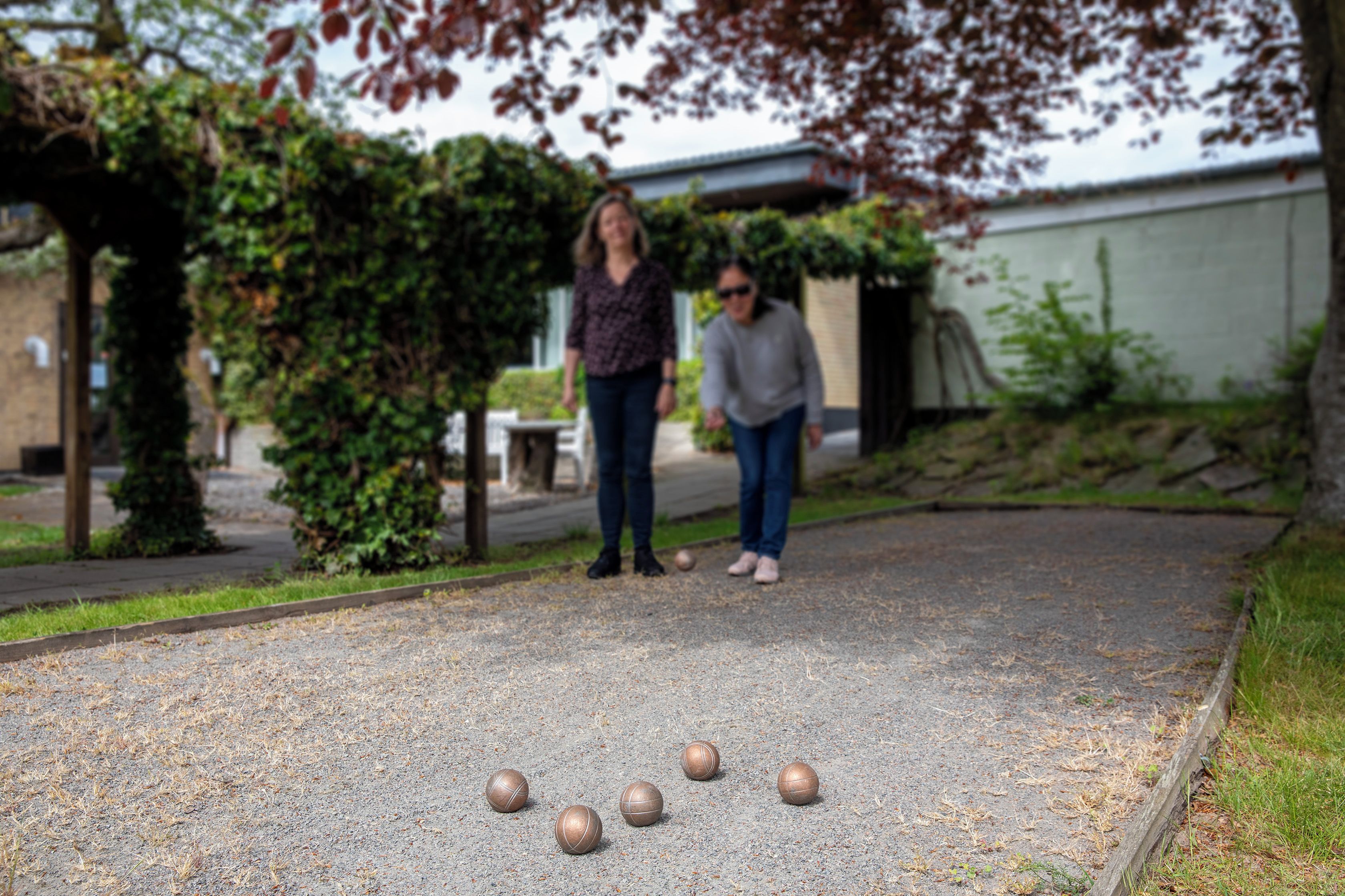 A courtyard with a gravel surface, three metal balls, and two people standing.
