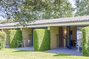 Un edificio con tetto in tegole, pareti in mattoni e un patio con tavoli e sedie.