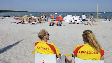 Escena de playa con gente relajándose y tomando el sol.