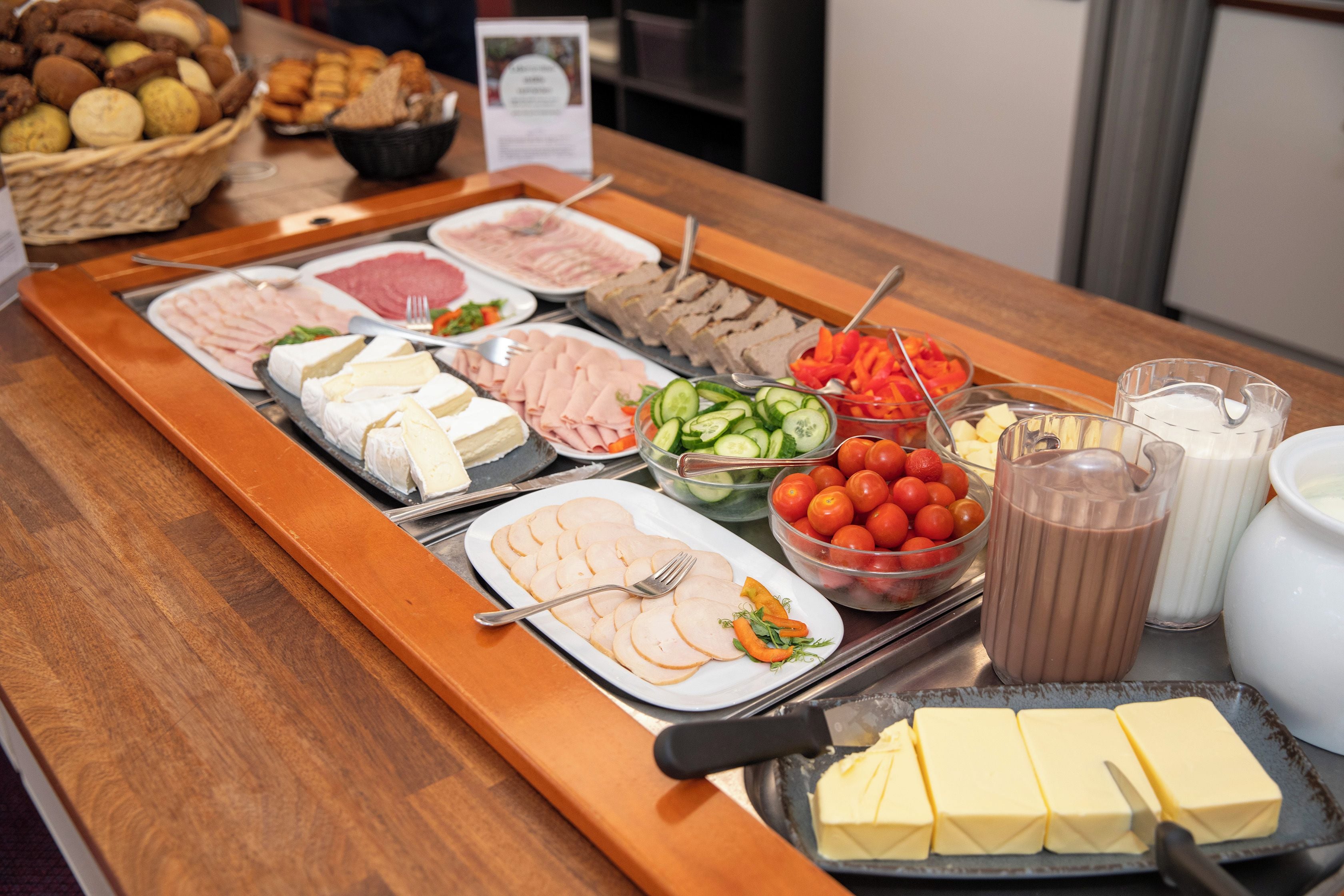 Un tavolo del buffet con diversi cibi, tra cui carni, formaggi, verdure e bevande.