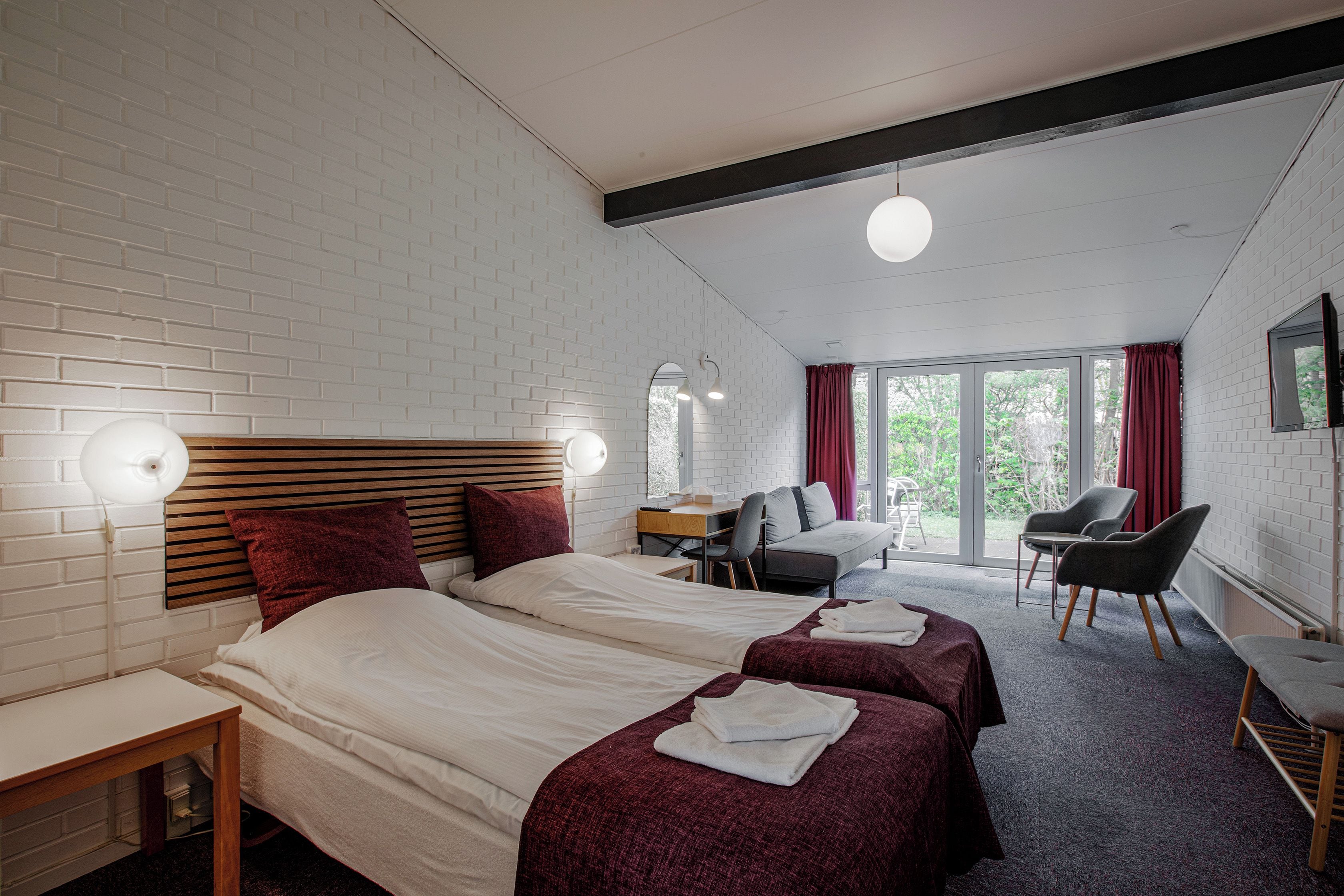 A hotel room with a bed, a desk, a chair, and a large window.
